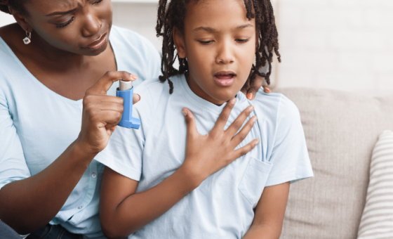 On voit un enfant en train de faire une crise d'asthme, il a du mal à respirer, a mère lui tend de la ventoline.