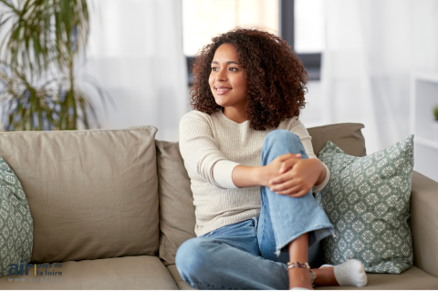 Une femme est assise sur un canapé et sourit